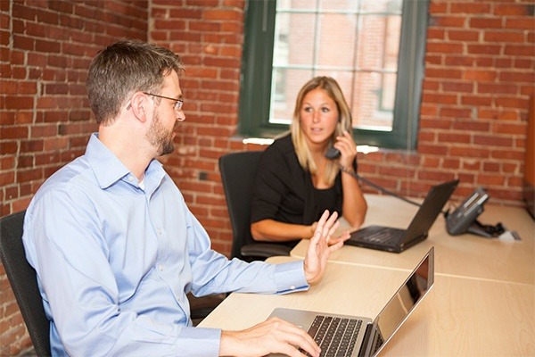Experienced legal advisors engaged in a professional consultation in a coworking office with a classic brick wall backdrop, showcasing the blend of traditional and modern elements in legal workspaces.